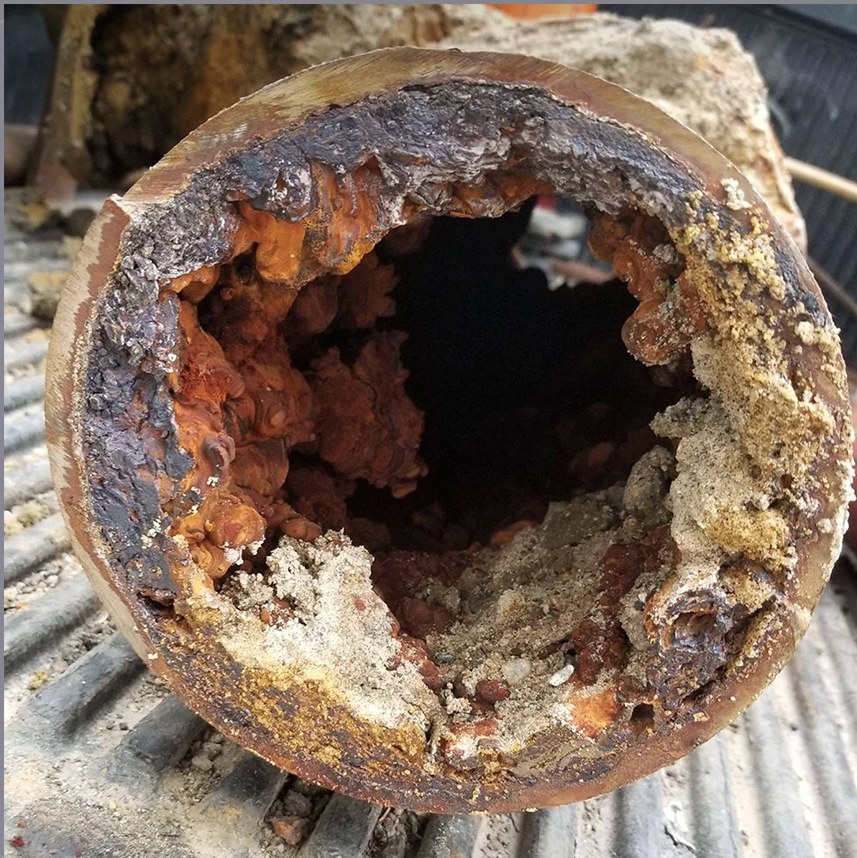 A real supply pipe after years of service, nearly closed with rust, scale, and sediment